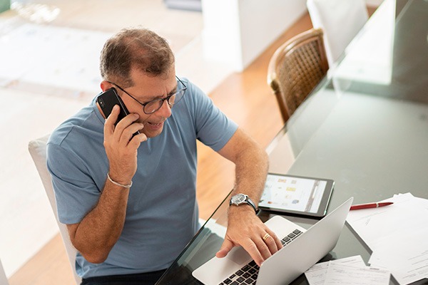 Man at computer on phone at home