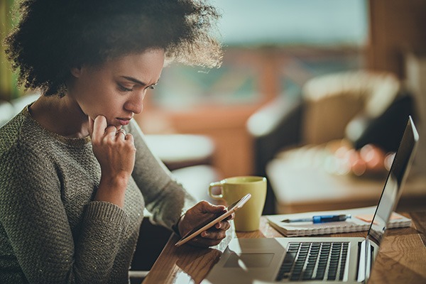 Pensive woman looking at smart phone