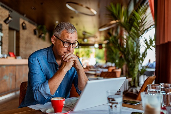 Thoughtful man at laptop in cafe